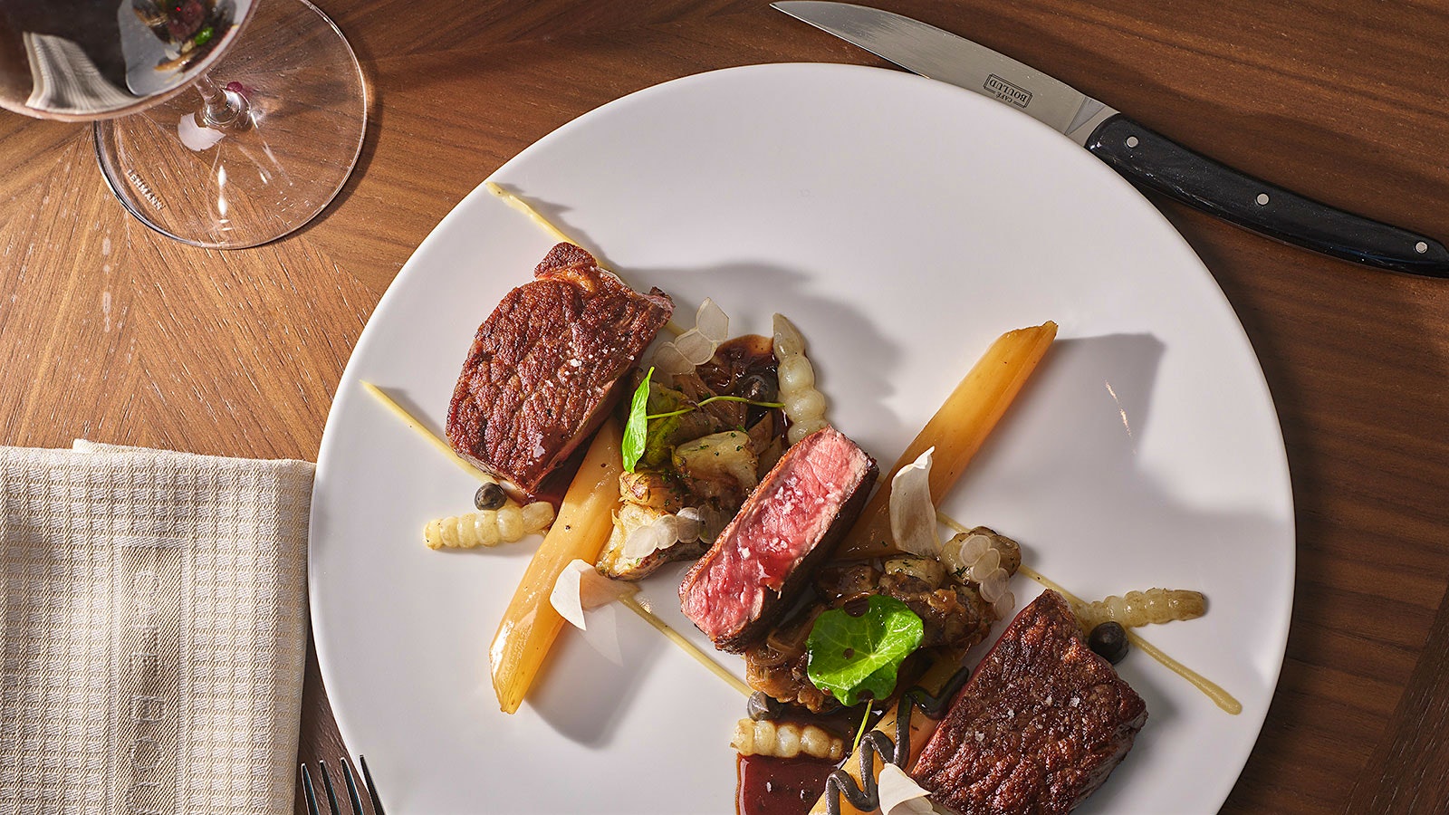 Plate of short ribs next to a glass of red wine
